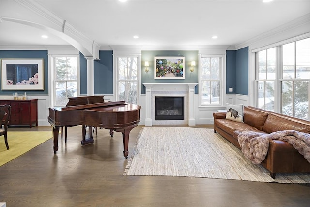 sitting room featuring a wealth of natural light, wood finished floors, a glass covered fireplace, and ornamental molding