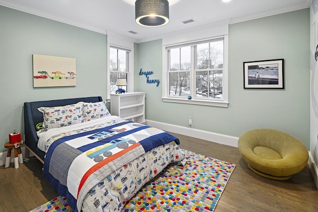 bedroom featuring visible vents, crown molding, baseboards, and wood finished floors