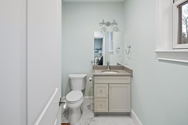 bathroom with vanity, toilet, baseboards, and marble finish floor