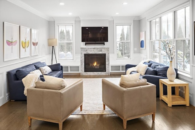 living area featuring a high end fireplace, crown molding, recessed lighting, wainscoting, and wood finished floors