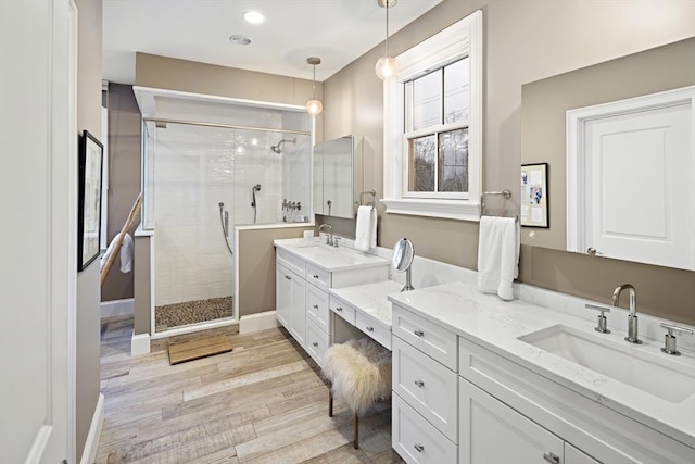 bathroom with a stall shower, wood finished floors, recessed lighting, baseboards, and vanity