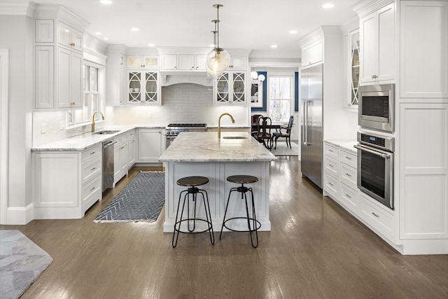 kitchen with a sink, built in appliances, and white cabinets