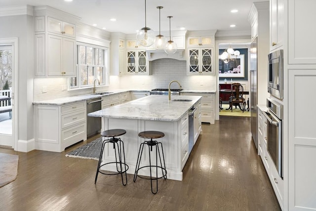 kitchen featuring white cabinetry, stainless steel appliances, an island with sink, and a sink