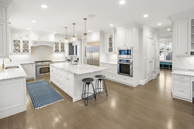 kitchen with white cabinetry, built in appliances, and a sink