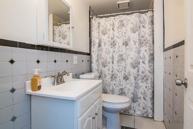 full bath with toilet, curtained shower, tile walls, tile patterned flooring, and vanity