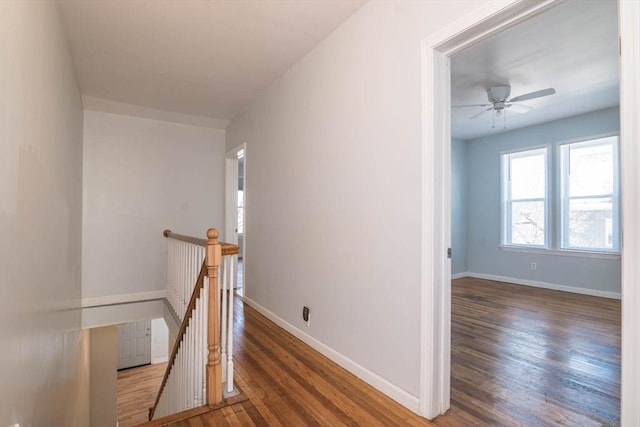 hallway with wood finished floors, an upstairs landing, and baseboards