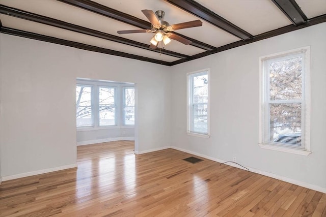 spare room featuring beamed ceiling, baseboards, visible vents, and light wood finished floors