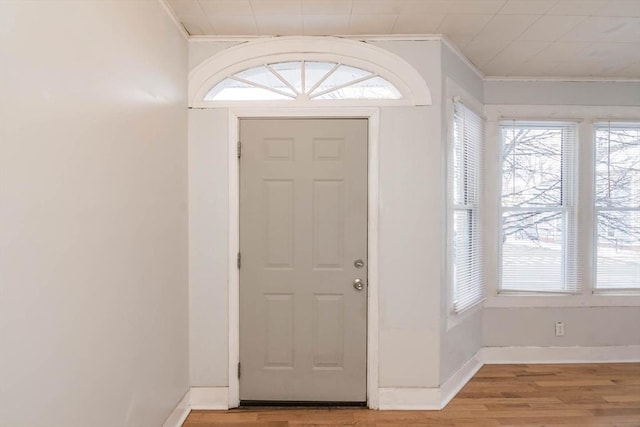 entryway with light wood-style flooring, baseboards, and ornamental molding