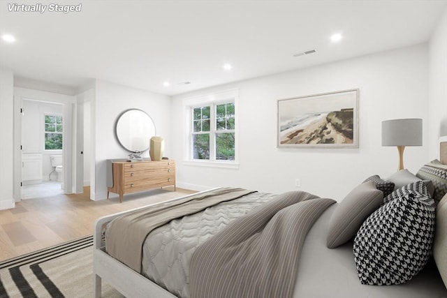 bedroom with ensuite bath and light hardwood / wood-style flooring