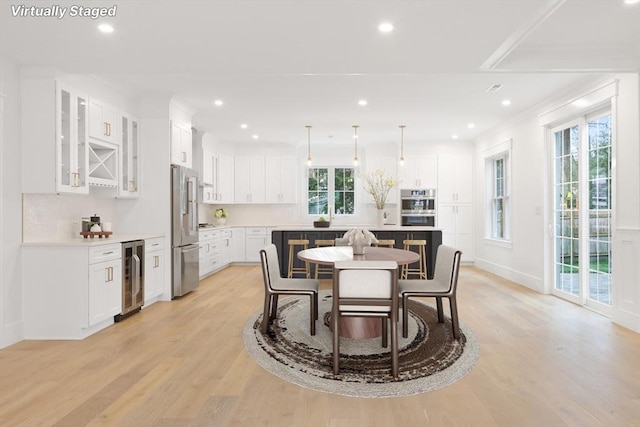 dining area with wine cooler, ornamental molding, and light wood-type flooring