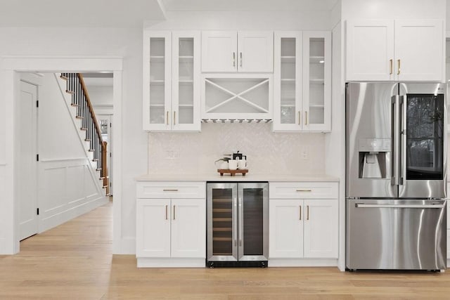 bar with wine cooler, stainless steel fridge, and white cabinets