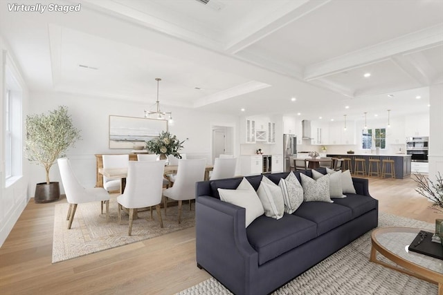 living room with coffered ceiling, beam ceiling, a chandelier, and light hardwood / wood-style flooring