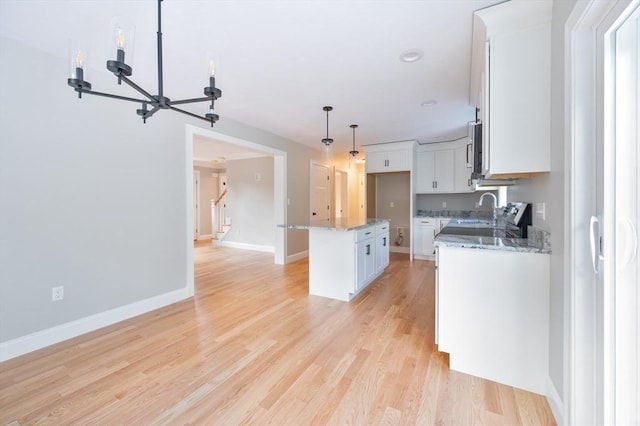 142 Tispaquin St, Middleboro, MA 02346 - kitchen featuring a sink, white cabinetry, light stone counters, hanging light fixtures, and light wood finished floors