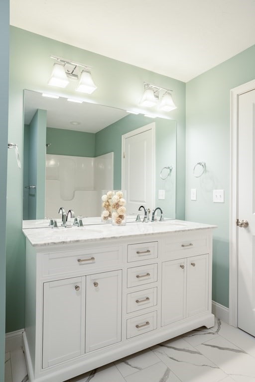 bathroom with tile flooring, dual sinks, and vanity with extensive cabinet space