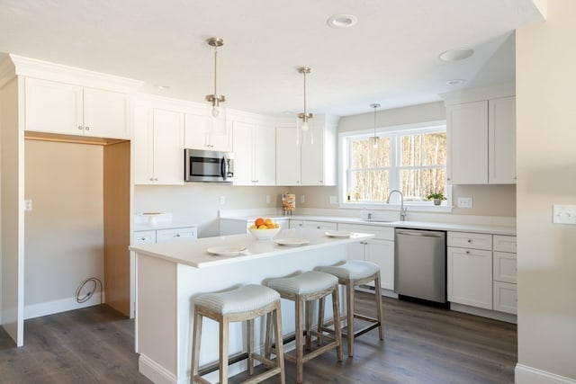 kitchen featuring a center island, white cabinetry, stainless steel appliances, dark hardwood / wood-style floors, and pendant lighting