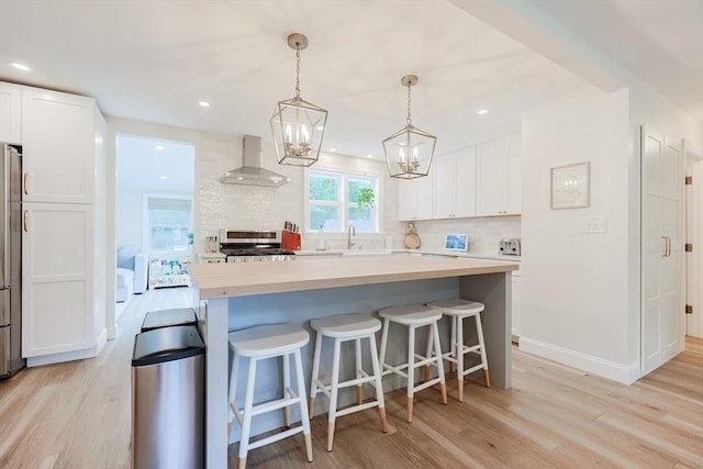 29 Regal St, Holliston, MA 01746 - kitchen featuring wall chimney exhaust hood, stove, light wood-type flooring, white cabinetry, and light countertops