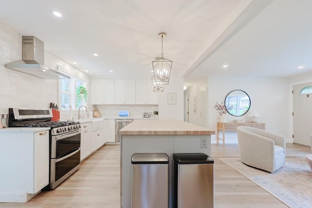 29 Regal St, Holliston, MA 01746 - kitchen featuring appliances with stainless steel finishes, island exhaust hood, white cabinetry, light countertops, and light wood-style flooring