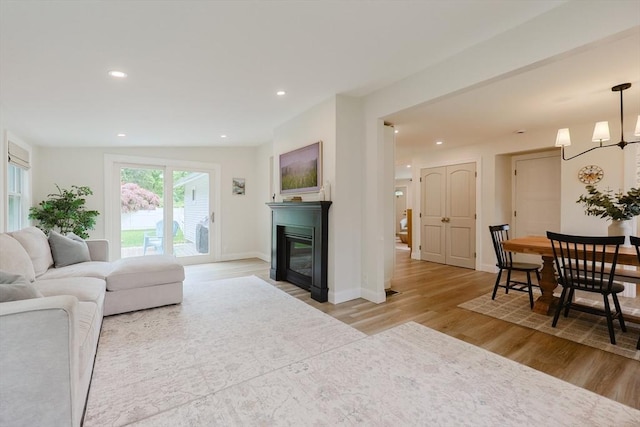 29 Regal St, Holliston, MA 01746 - living area with a glass covered fireplace, light wood-style floors, a chandelier, recessed lighting, and baseboards