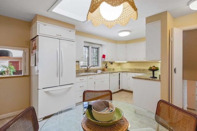 kitchen with light stone counters, white appliances, light floors, and white cabinetry