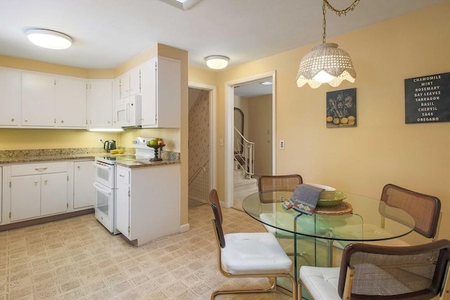 kitchen featuring white appliances, hanging light fixtures, light stone countertops, light floors, and white cabinetry