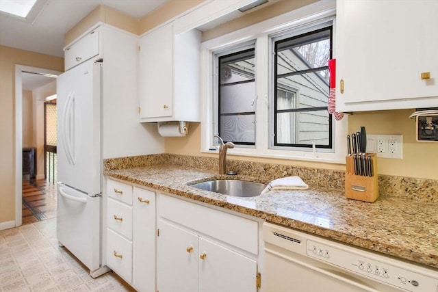 kitchen featuring a skylight, white cabinetry, a sink, light stone countertops, and white appliances