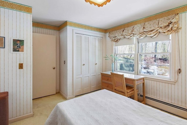 bedroom with a closet, light colored carpet, wooden walls, and baseboard heating