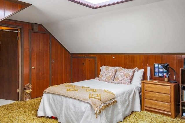 bedroom featuring lofted ceiling, wood walls, and carpet