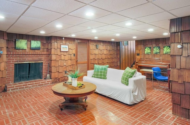 living room featuring wood walls, brick floor, a fireplace, and recessed lighting