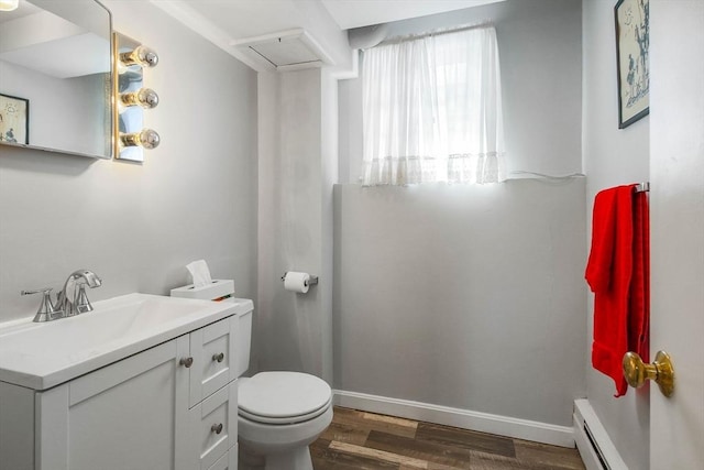 half bath with toilet, baseboards, a baseboard heating unit, and wood finished floors