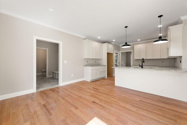 kitchen with white cabinetry, hanging light fixtures, crown molding, light stone countertops, and light wood-type flooring