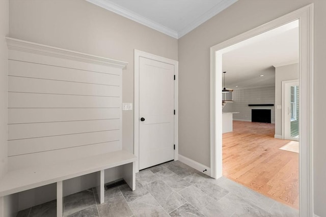 mudroom featuring crown molding, a fireplace, and light hardwood / wood-style floors