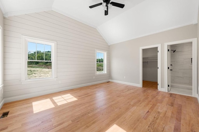 unfurnished bedroom featuring lofted ceiling, a walk in closet, light hardwood / wood-style floors, and a closet