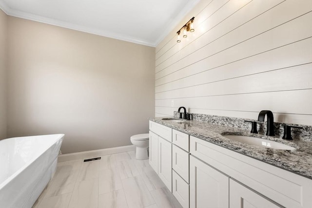 bathroom featuring vanity, ornamental molding, a bathtub, and toilet