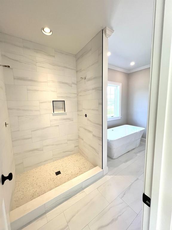 bathroom featuring ornamental molding and plus walk in shower