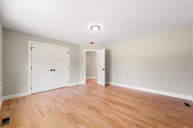 unfurnished bedroom with a closet and light wood-type flooring