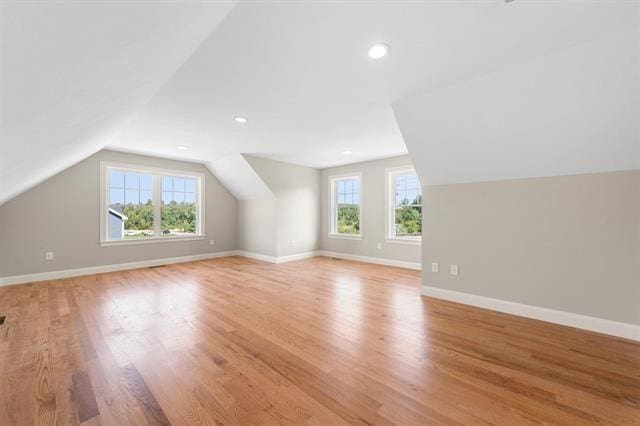 bonus room with vaulted ceiling, a healthy amount of sunlight, and light hardwood / wood-style floors