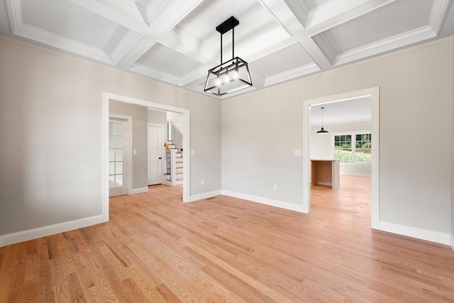 unfurnished dining area featuring beamed ceiling, ornamental molding, coffered ceiling, and light wood-type flooring