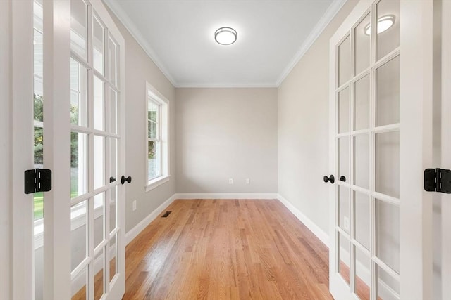 spare room featuring light hardwood / wood-style flooring, ornamental molding, and french doors