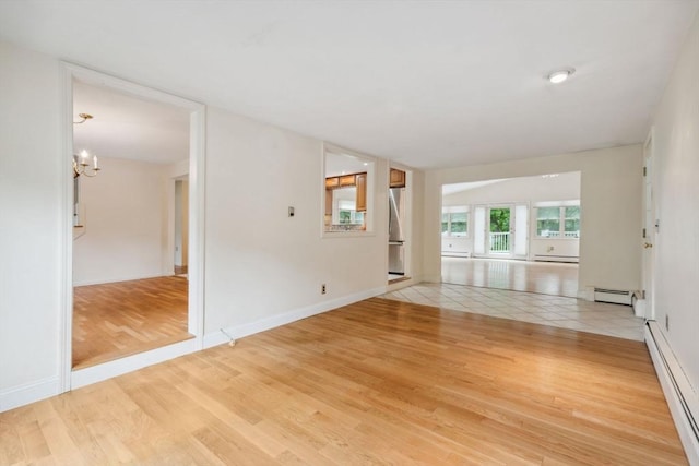 103 Central St, Newbury, MA 01922 - empty room featuring a baseboard heating unit, a chandelier, light wood finished floors, and baseboard heating