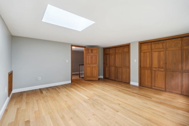 103 Central St, Newbury, MA 01922 - unfurnished bedroom with multiple closets, light wood finished floors, and a skylight
