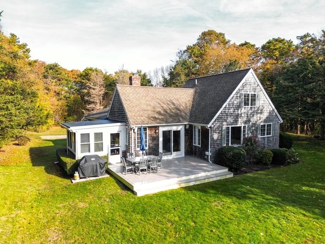 rear view of house featuring a shingled roof, a lawn, and a chimney