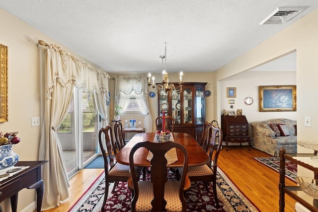 114 Cypress Dr, Swansea, MA 02777 - dining space featuring a chandelier, light wood-style floors, and a textured ceiling