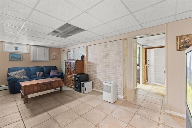 114 Cypress Dr, Swansea, MA 02777 - living area featuring light tile patterned flooring, a paneled ceiling, and brick wall
