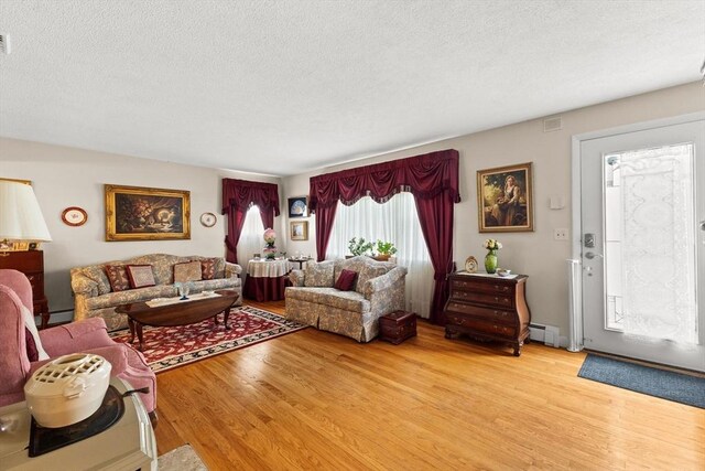 114 Cypress Dr, Swansea, MA 02777 - living area with a textured ceiling, light wood-style flooring, and a baseboard radiator