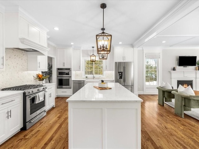 kitchen featuring stainless steel appliances, a center island, white cabinets, and decorative light fixtures