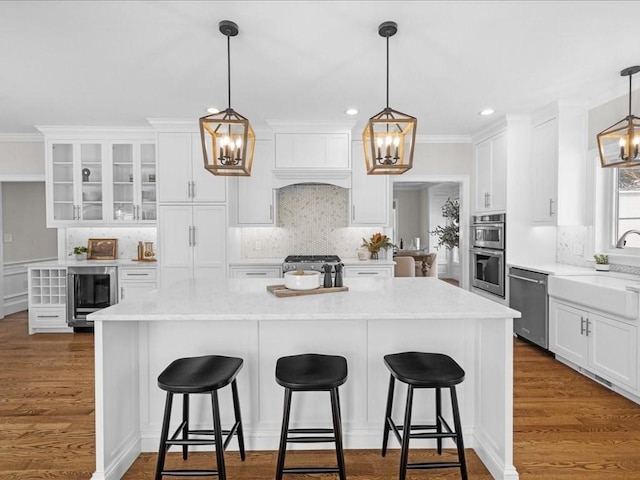 kitchen featuring premium range hood, stainless steel appliances, white cabinets, and a kitchen island