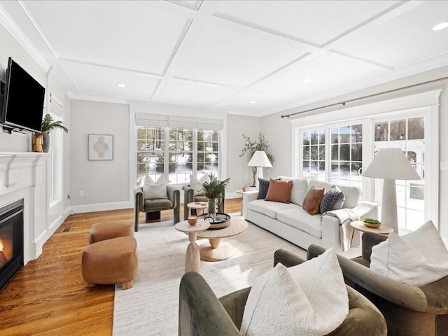 living room featuring ornamental molding, coffered ceiling, a wealth of natural light, and light wood-type flooring