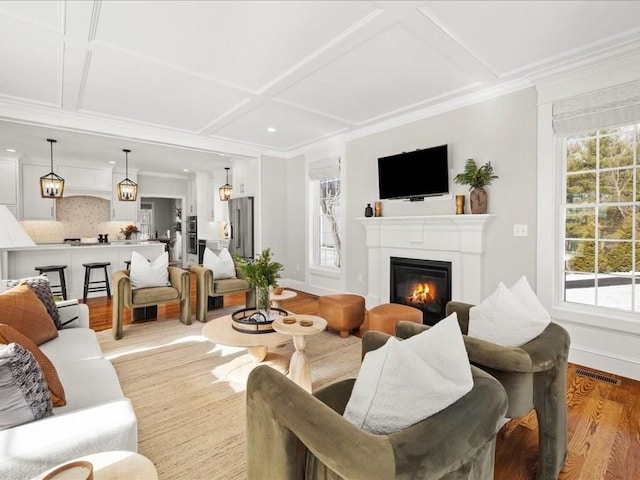 living room with coffered ceiling, crown molding, and light hardwood / wood-style floors