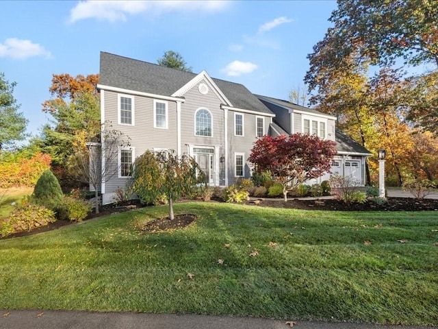 colonial house featuring a garage and a front lawn