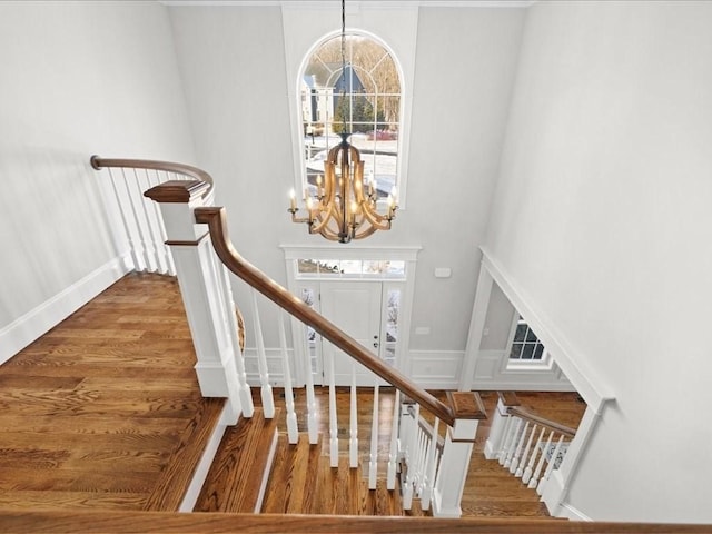 stairs with hardwood / wood-style flooring and a notable chandelier